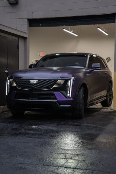 Lila SUV mit moderner Frontpartie, geparkt in einer Garage.